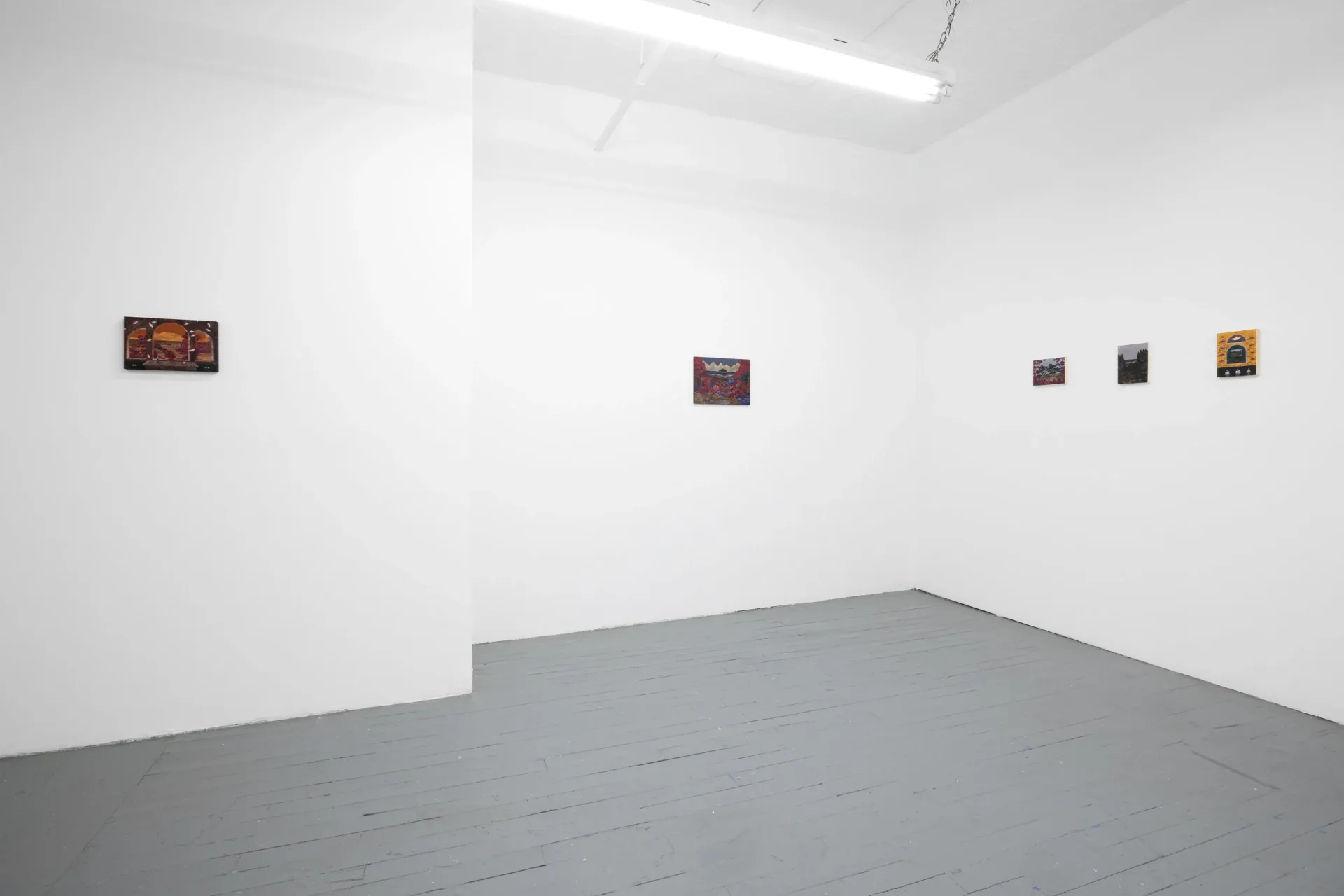 Gallery interior with white walls and gray floor displaying five small framed artworks mounted horizontally across the wall.