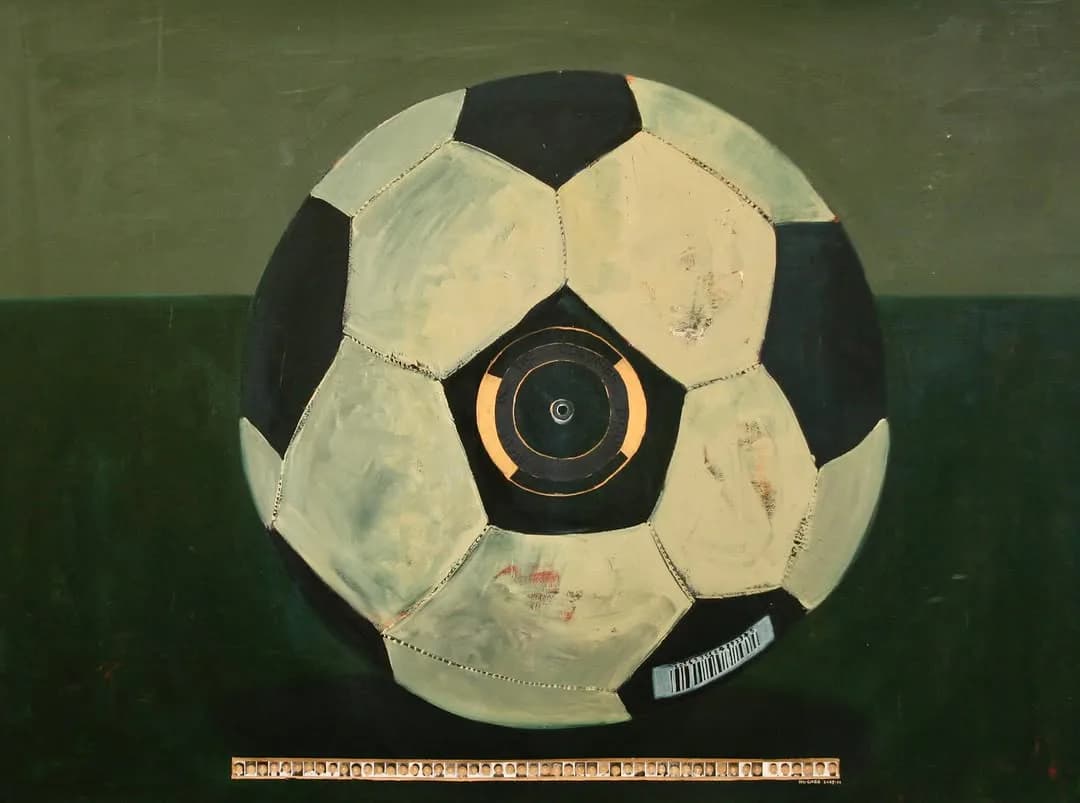 Vintage soccer ball with black and white panels and gold circular center medallion, shown against green background with measurement scale.