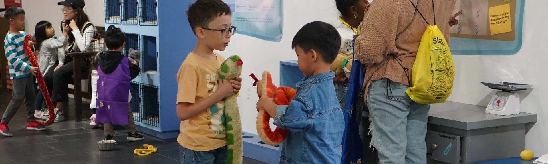 Children interact with hands-on exhibits in a bright gallery space at Staten Island Children's Museum, with educational displays and activity stations visible.