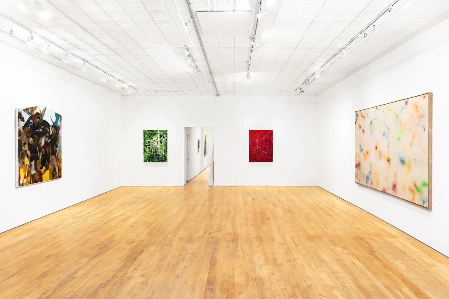 Storage gallery interior showing white walls, wooden floor, and multiple artworks of varying sizes displayed at different heights.