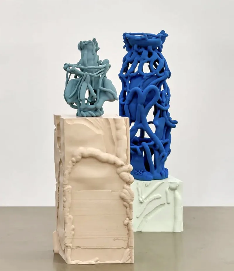 Three sculptural forms in white, blue, and pale green ceramic or plaster—geometric and organic shapes stacked on rectangular bases.