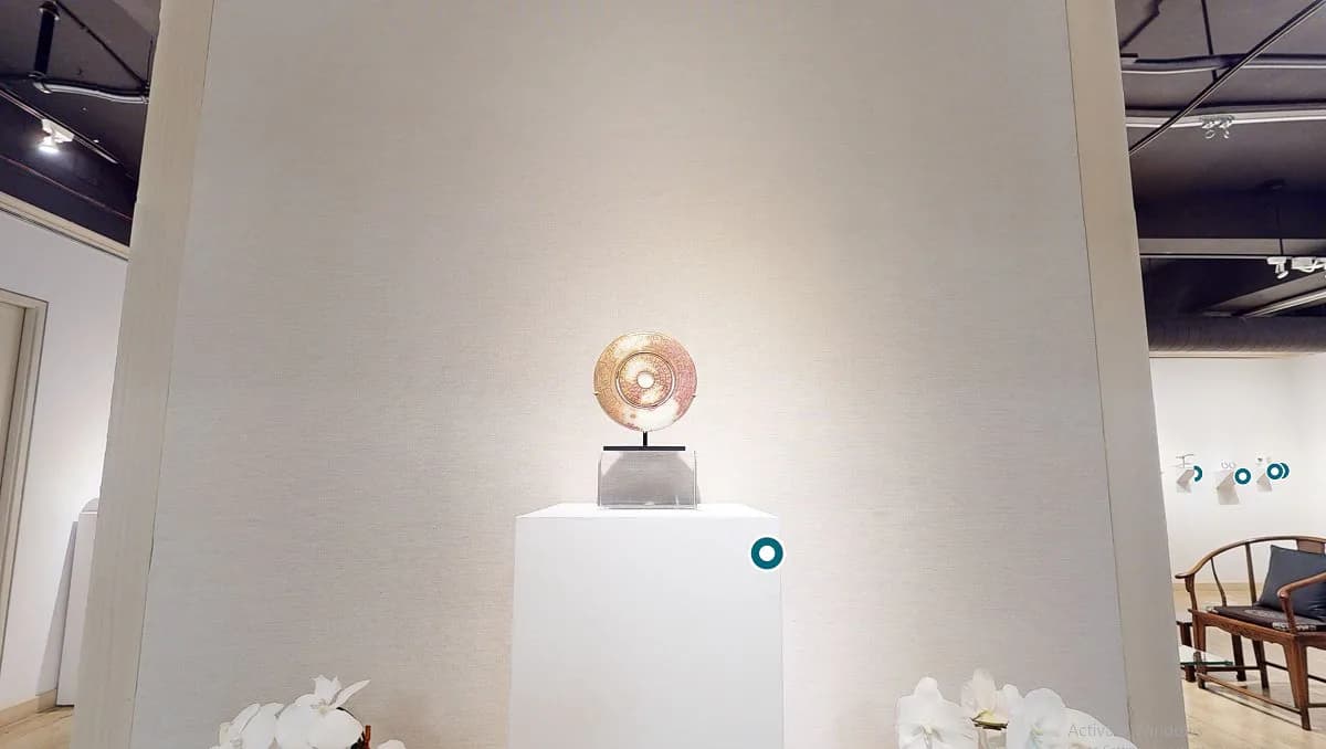 White gallery wall with a sculptural bronze head mounted on a pedestal, spotlit from above, in Throckmorton Fine Art's interior space.