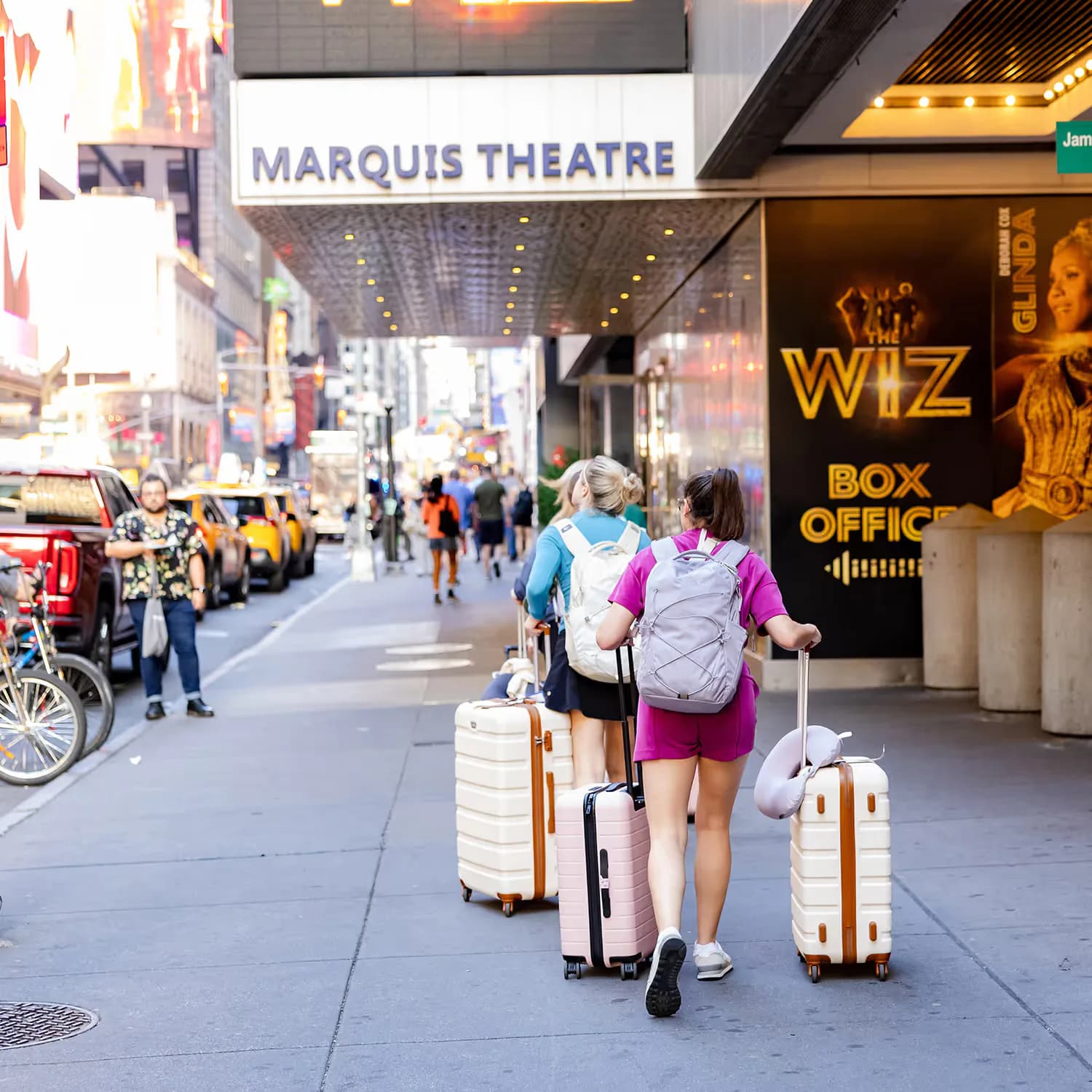 Marquis Theatre marquee and street scene in Times Square with pedestrians and Wiz Broadway show signage visible.