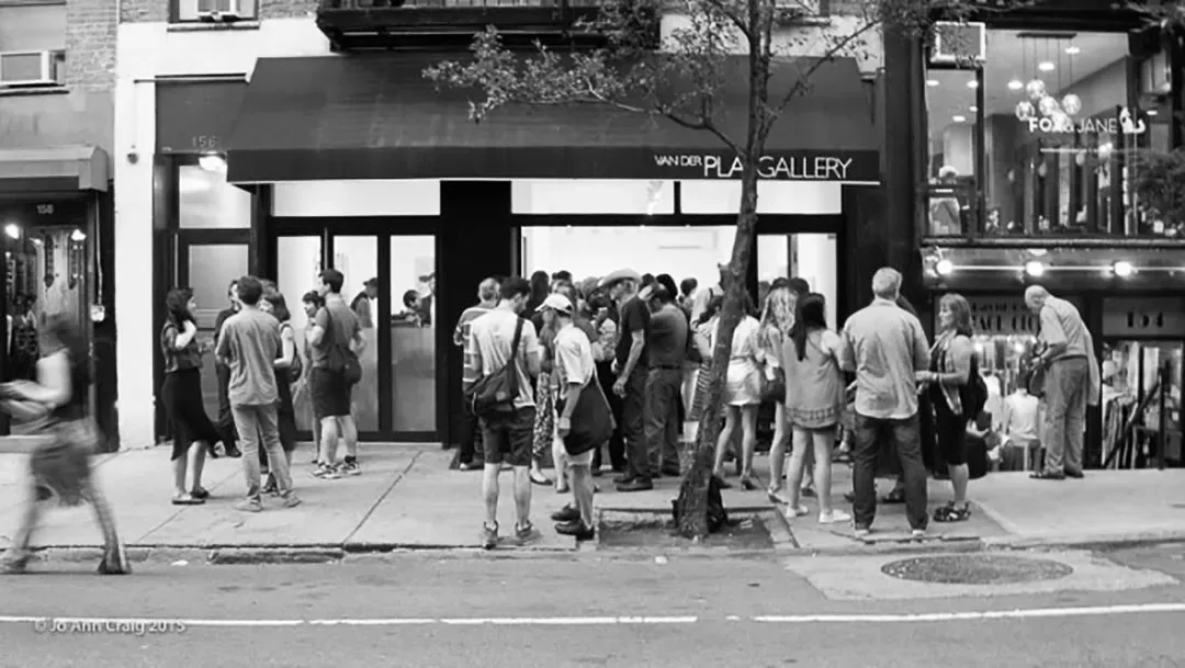 Black and white photograph of Van Der Plas Gallery storefront with large crowd of people gathered outside on the street.