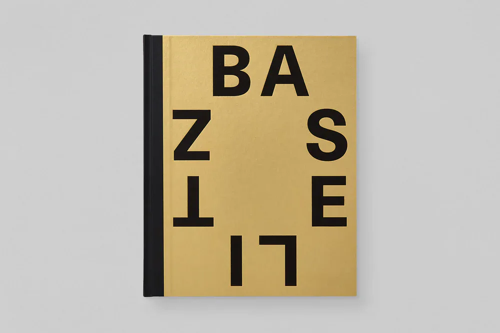 Yellow hardcover book with black letters arranged in geometric pattern reading 'BASELESS' on its spine.