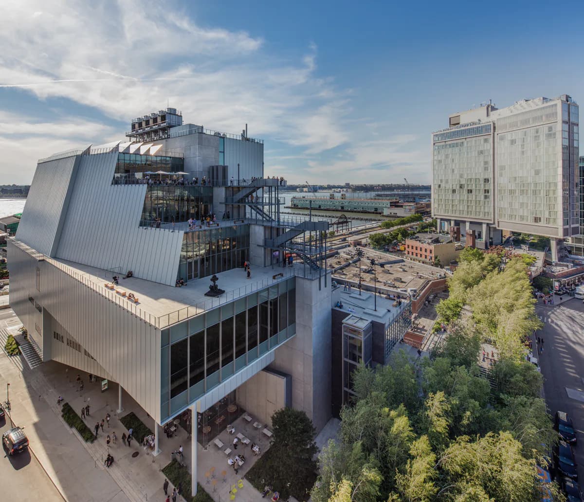 Exterior photograph of the Whitney Museum of American Art's modern architecture in Chelsea, featuring distinctive tilted metal facade overlooking the High Line.